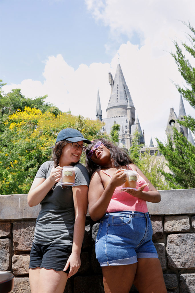 Two girls with butterbeer next to Hogwarts Castle