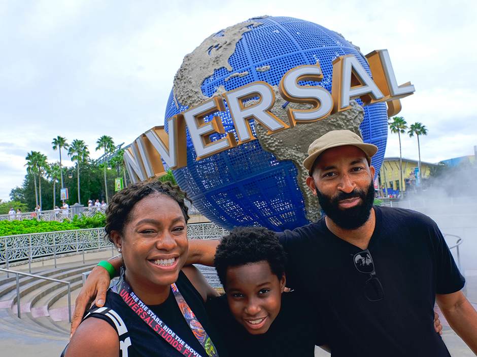 A family poses in front of the globe