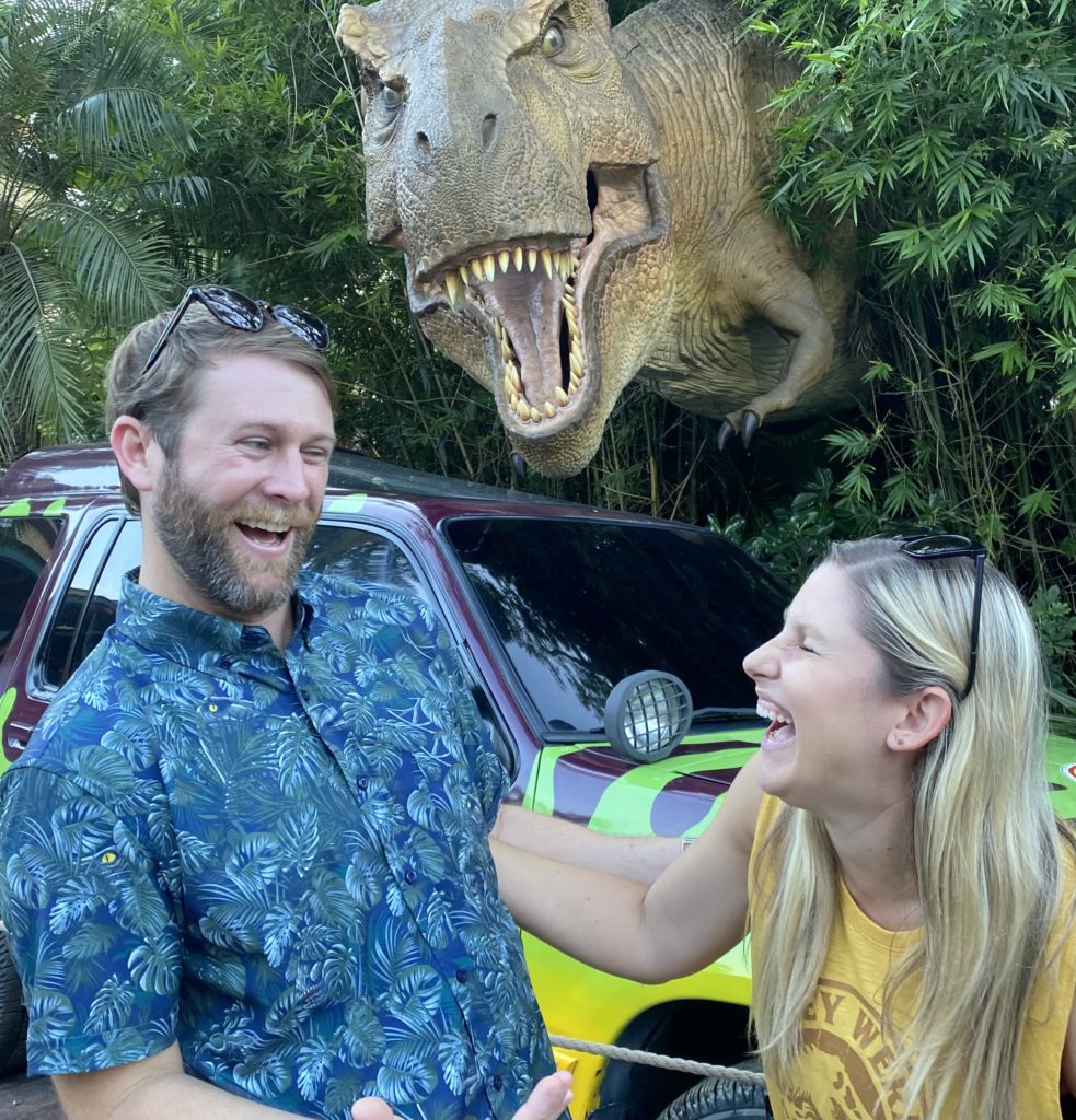 Two people pose with a dinosaur statue