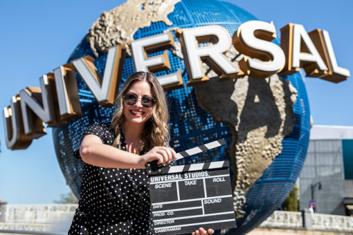 Woman holding clapboard in front of Universal Globe