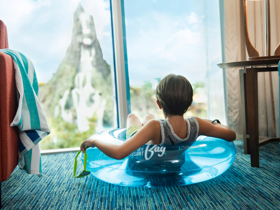 Boy sitting on float looking out the window to Volcano Bay