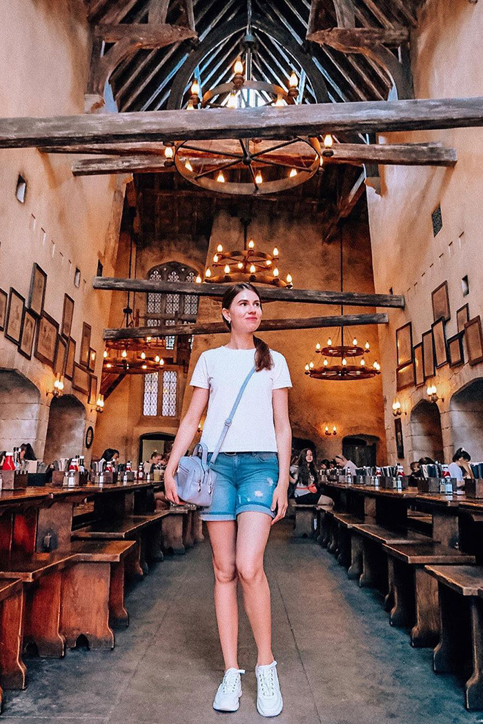 Woman stands in the middle of Leaky Cauldron