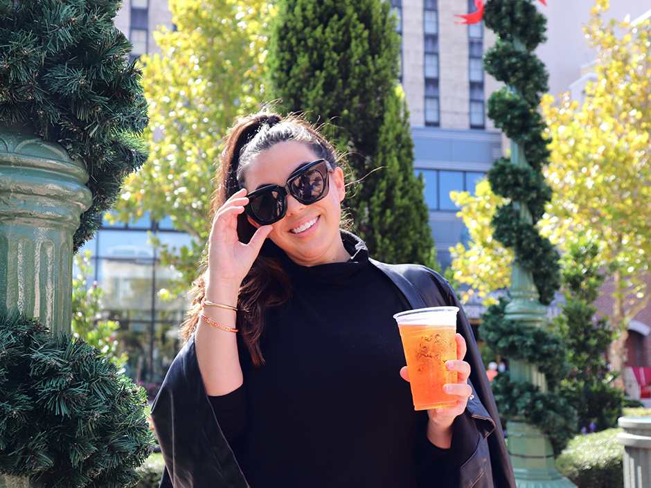 Woman holding drink and hand on sunglass