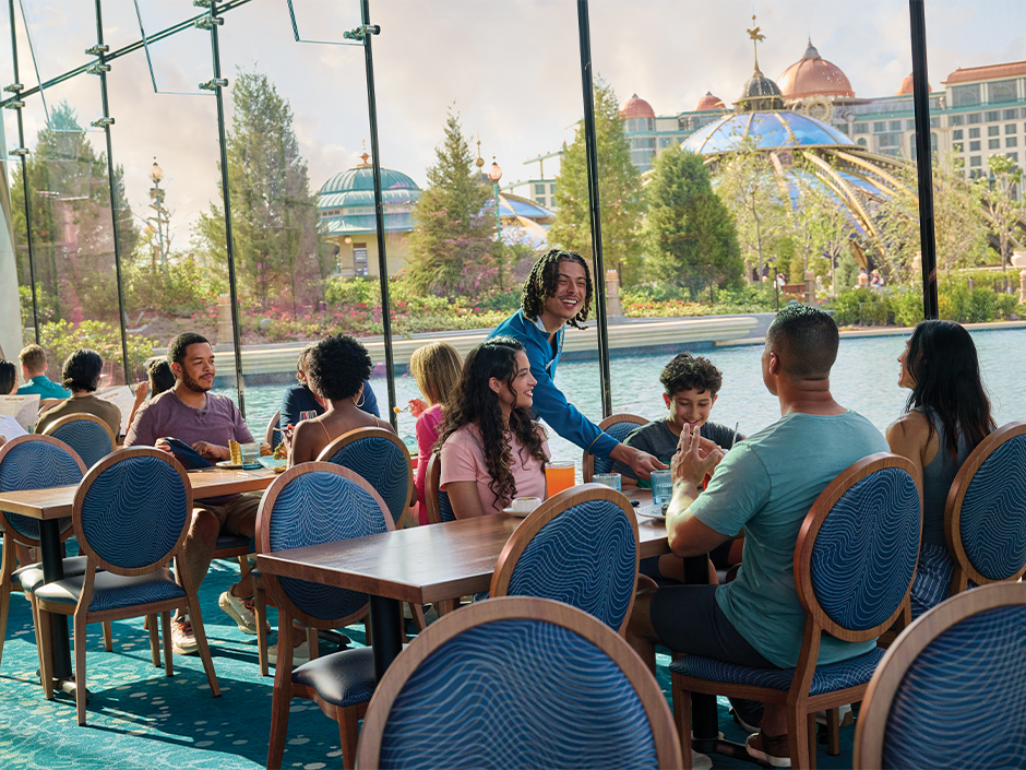 A family smiles and chats with a server at Atlantic Restaurant in Epic Universe