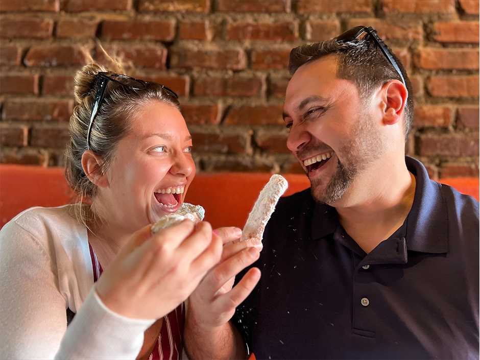 Man and woman eating beignets