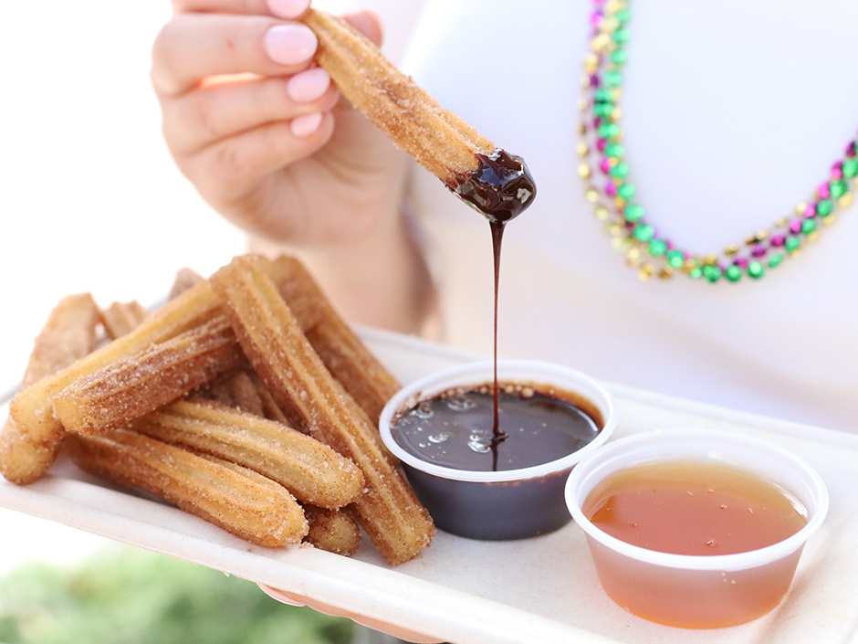 Hand holding Vegan Churros after dipping in chocolate sauce Universal Mardi Gras 2023