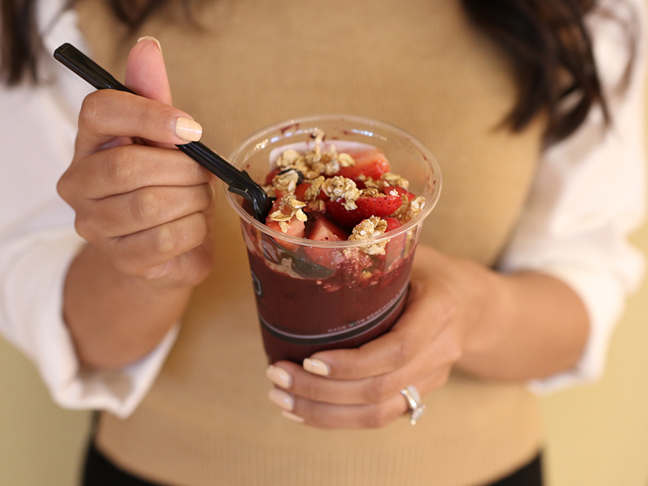 Woman holding spoon and Acai Bowl Shakes and Malt Shoppe CBBR