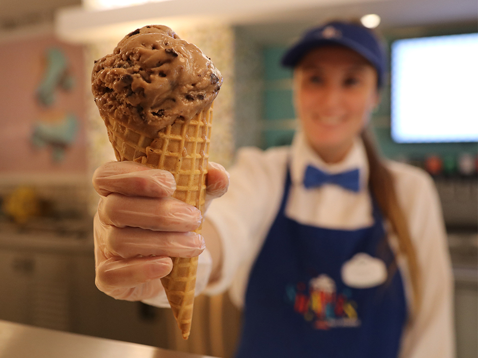 Server in blue apron handing ice cream on a cone