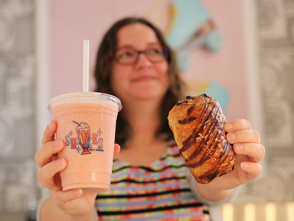 Woman holding smoothie and chocolate croissant 