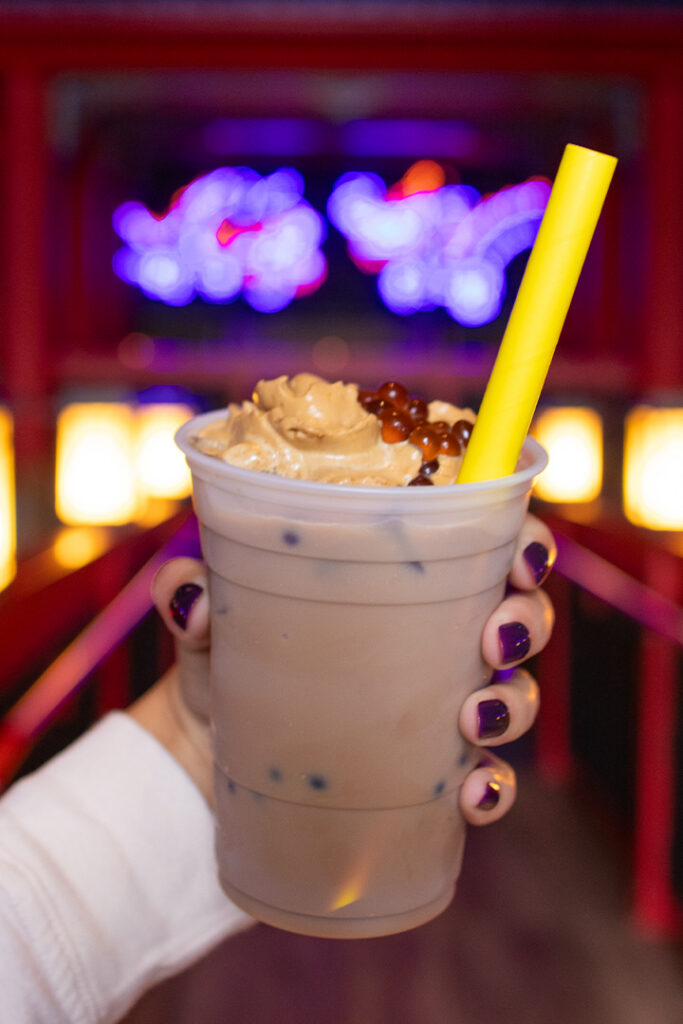 A hand holding up a Thai Boba inside The Blue Dragon Pan-Asian Restaurant