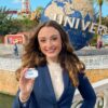 Headshot woman holding out her Universal badge with Universal Globe in the back