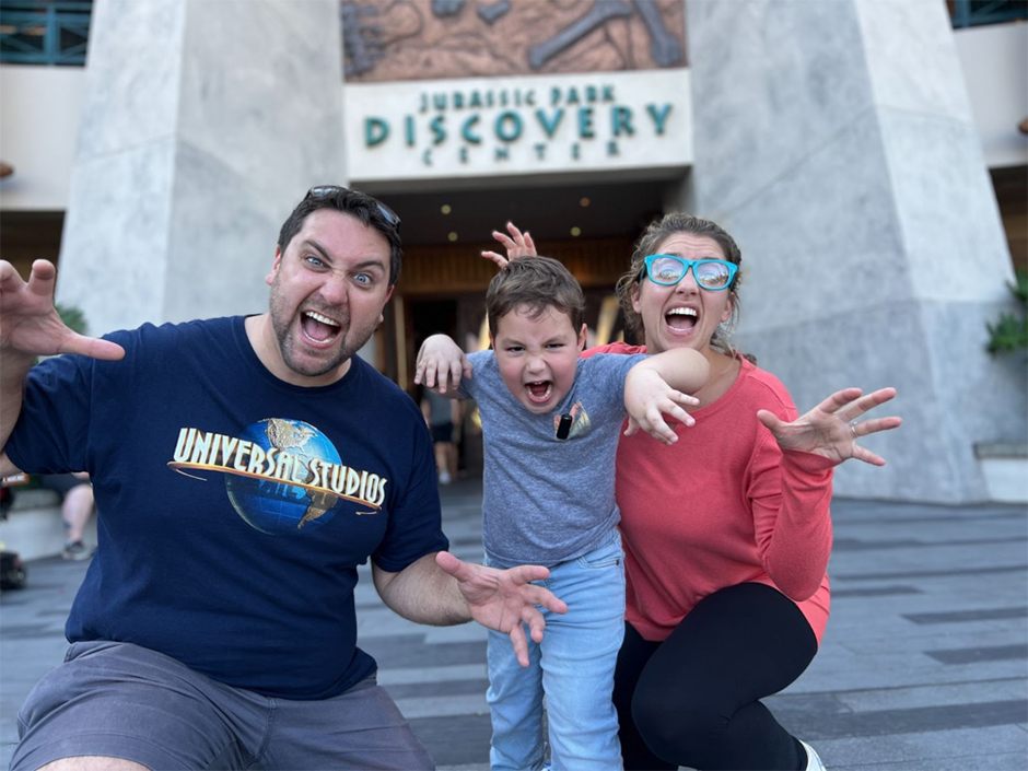 Podcast Hosts in front of Discovery Center in Jurassic Park with young boy
