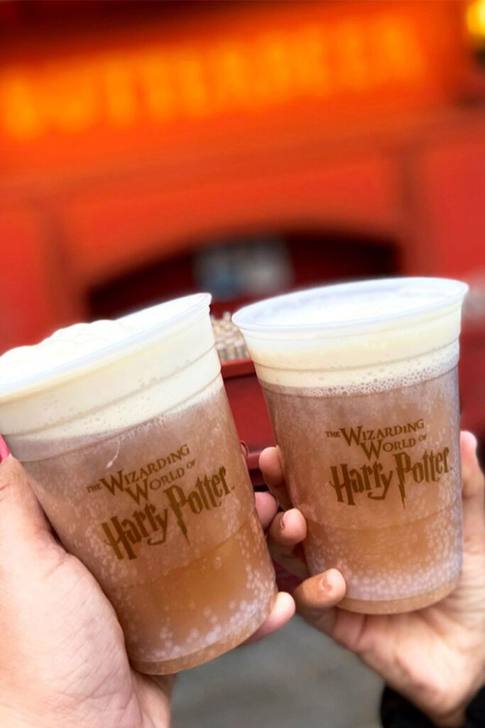 Two cups of frozen Butterbeer being cheers'ed in Harry Potter land in Hollywood