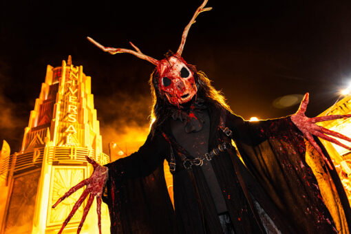 Scareactor in horned-mask standing in front of Universal Plaza sign