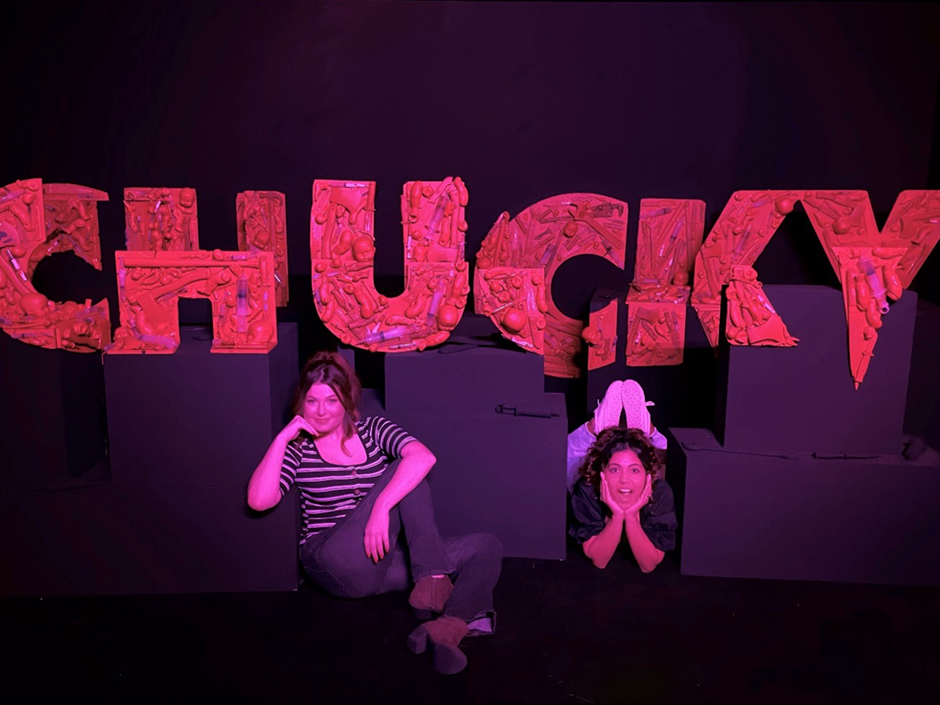 Two women pose with the Chucky logo