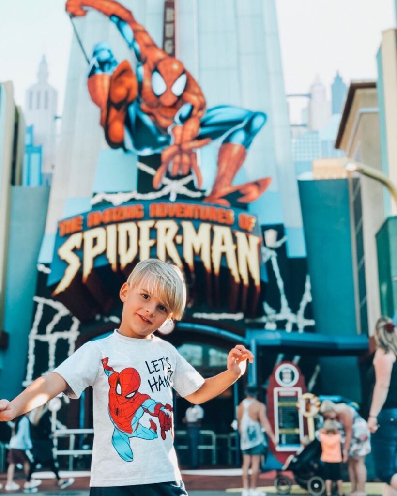 Boy stands in front of The Amazing Spider-Man attraction