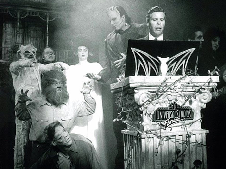 A man is seen speaking with Universal classic monsters behind him