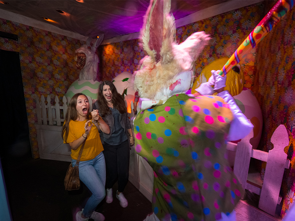 Demon Easter Bunny holds bat up to two guests in haunted house