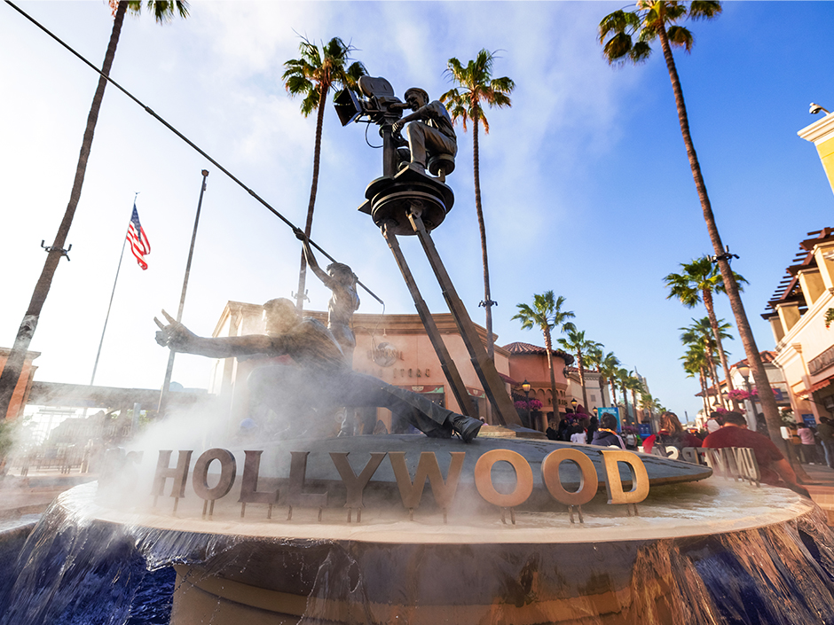 Close-up of fountain with statues of a director, a camera operator and an actor in it, and sign reading "Hollywood."