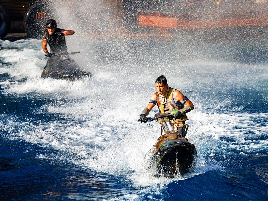 Two men on jet skis with water spraying everywhere.