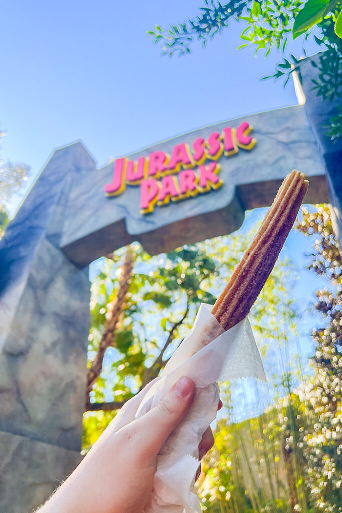 A churro in front of the Jurassic Park sign