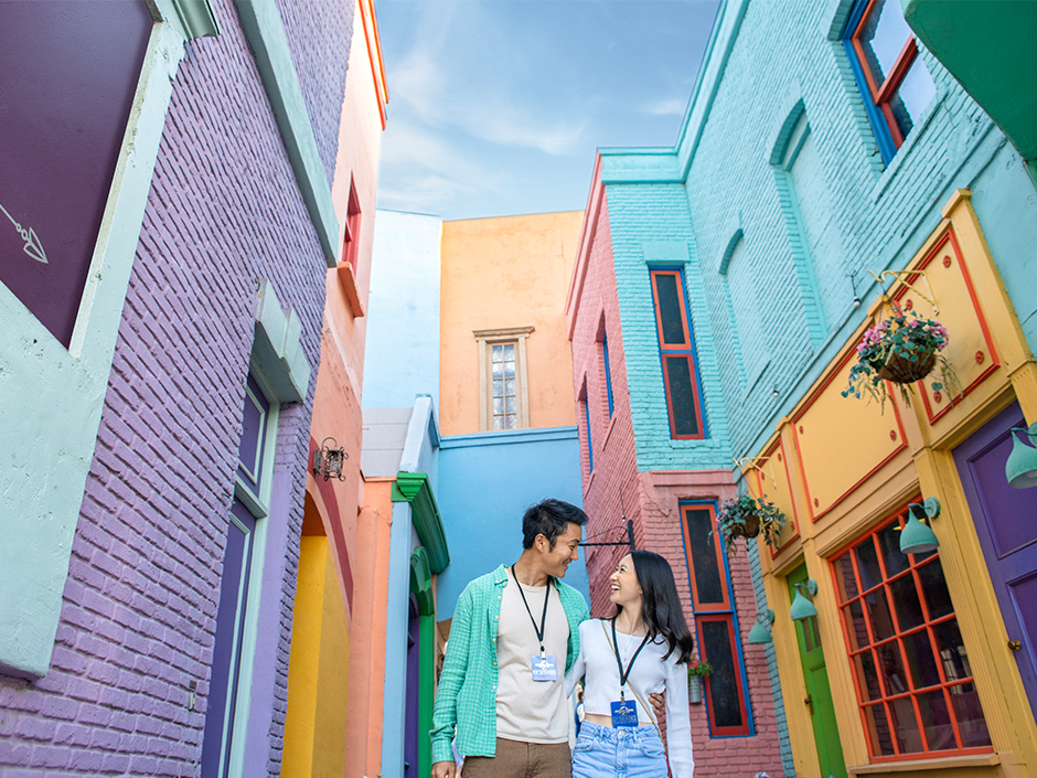 Two people walk together on colorful Little Europe set on Universal backlot.