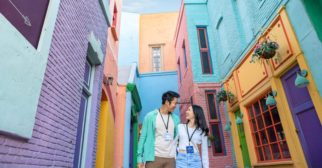 Two people walk together on colorful Little Europe set on Universal backlot.