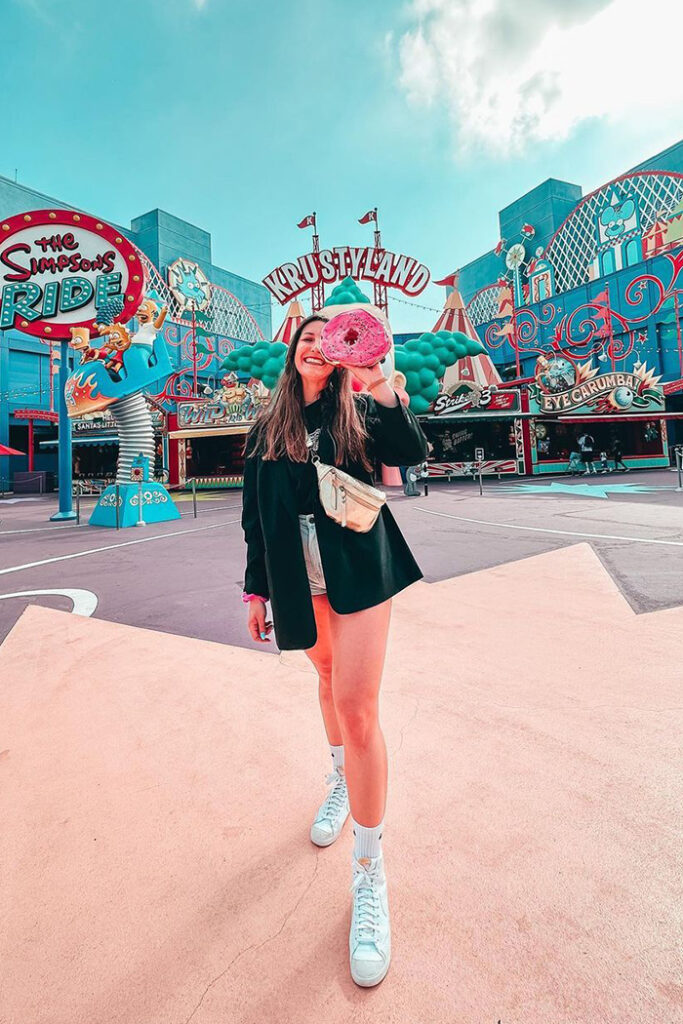 Park guest poses with The Big Pink donut in front of Krustyland.