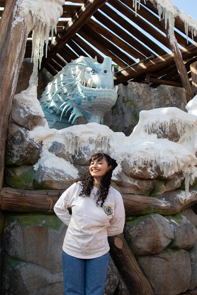 A guest poses in front of the Ice Dragon figure in Isle of Berk at Epic Universe