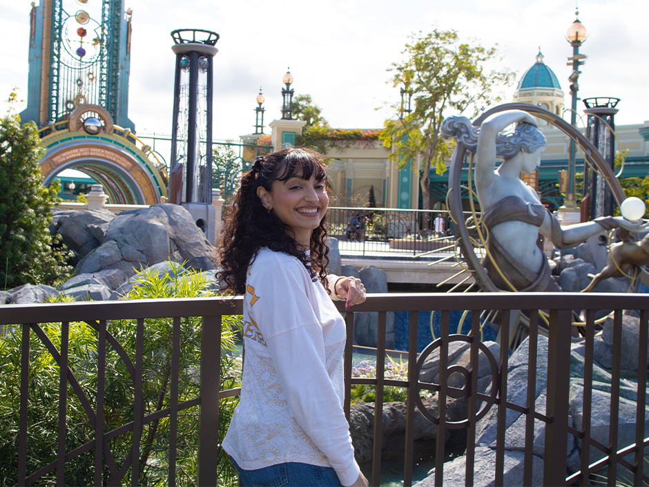 A guest smiles for a photo in the Celestial Park Court of the Moon at Universal Epic Universe
