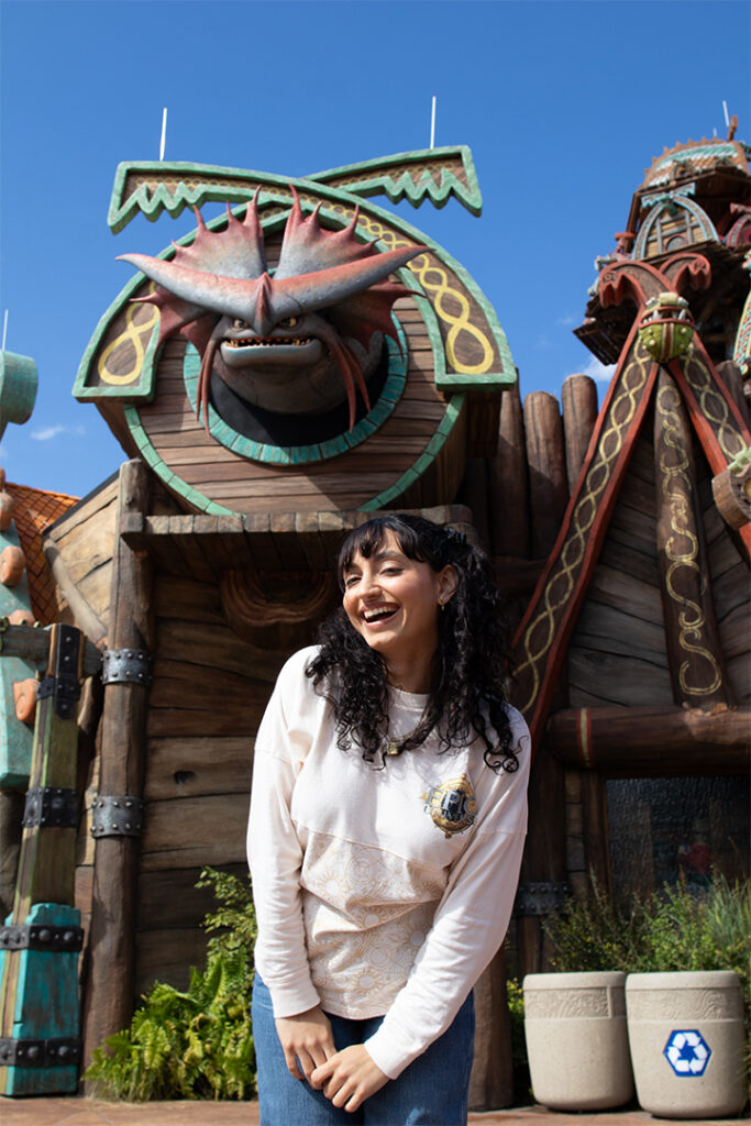 A guest poses in front of the Cloudjumper dragon figure in Isle of Berk at Epic Universe
