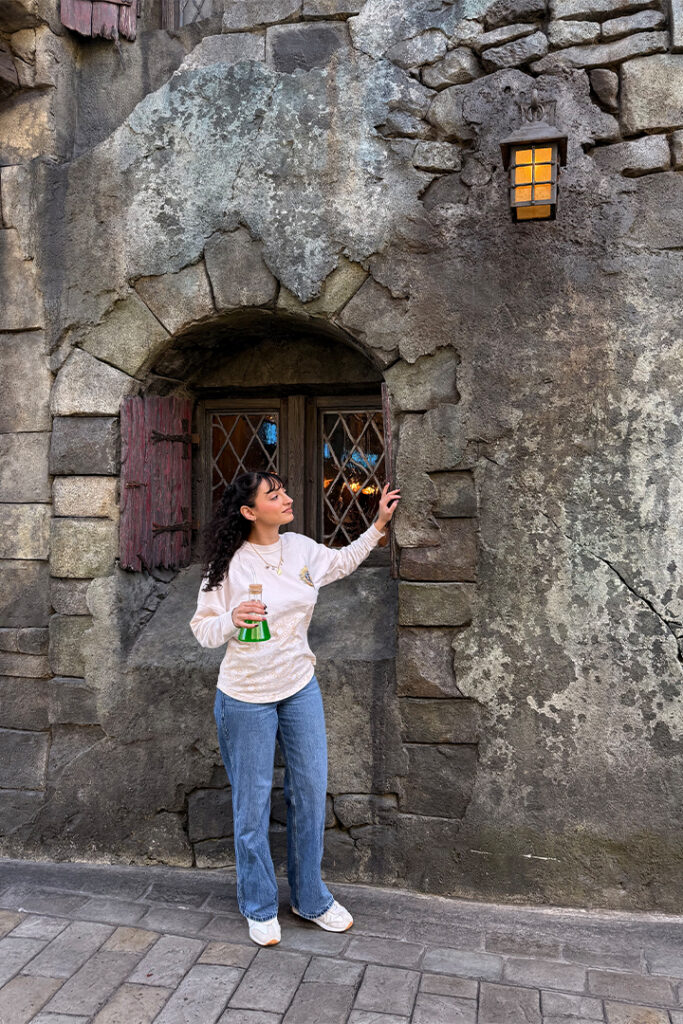 A guest poses with the Monocane Mocktail in Dark Universe at Universal Epic Universe