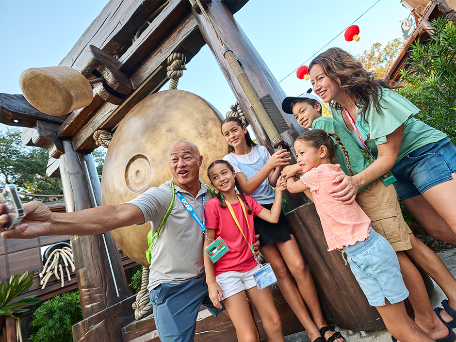 A family poses for a selfie in front of the gong at Po's Kung Fu Training Camp in Universal Studios Florida