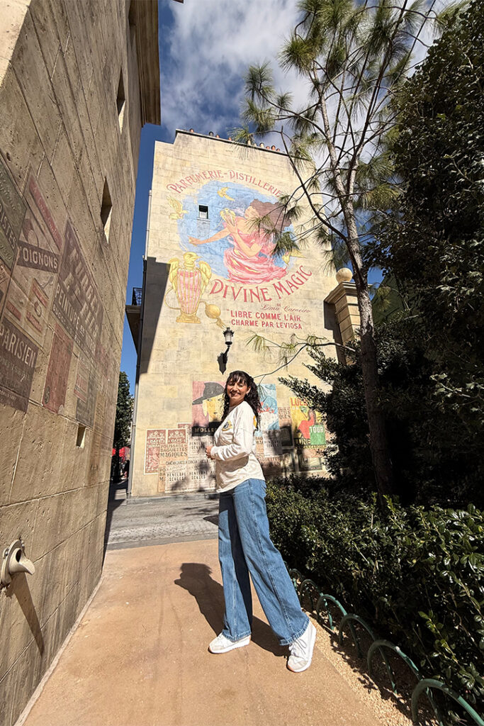A guest poses in front of a perfume advertisement on the wall in The Wizarding World of Harry Potter - Ministry of Magic in Epic Universe