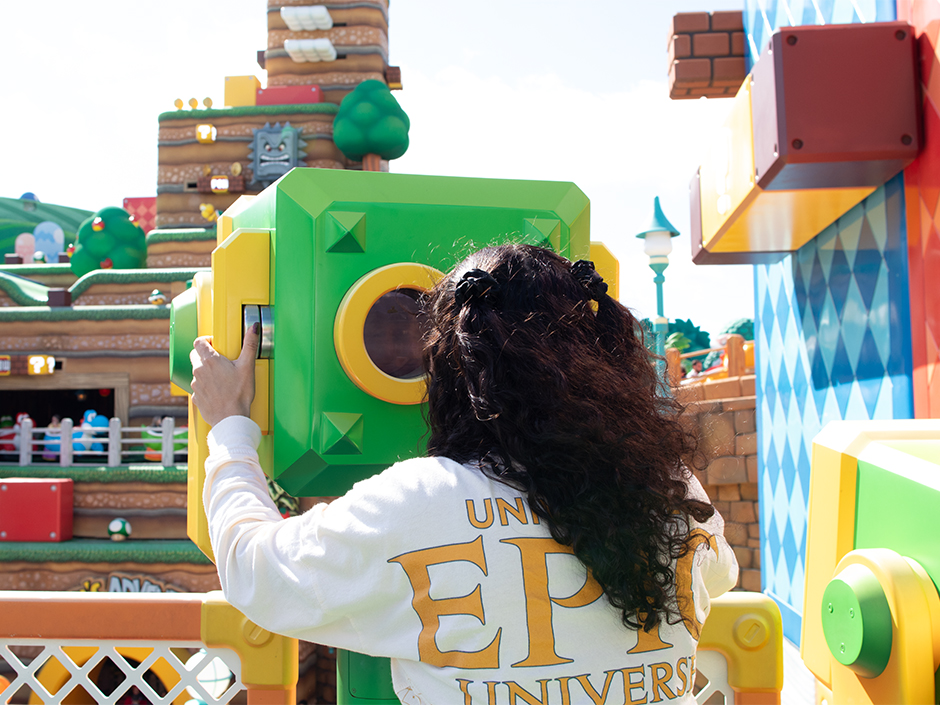 A guest peeks through the binoculars in SUPER NINTENDO WORLD at Universal Epic Universe