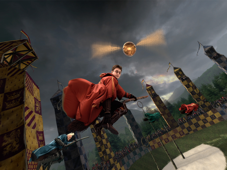 Harry Potter wearing a red robe on a broom with the golden snitch in center view on Harry Potter and the Forbidden Journey in the Wizarding World of Harry Potter.