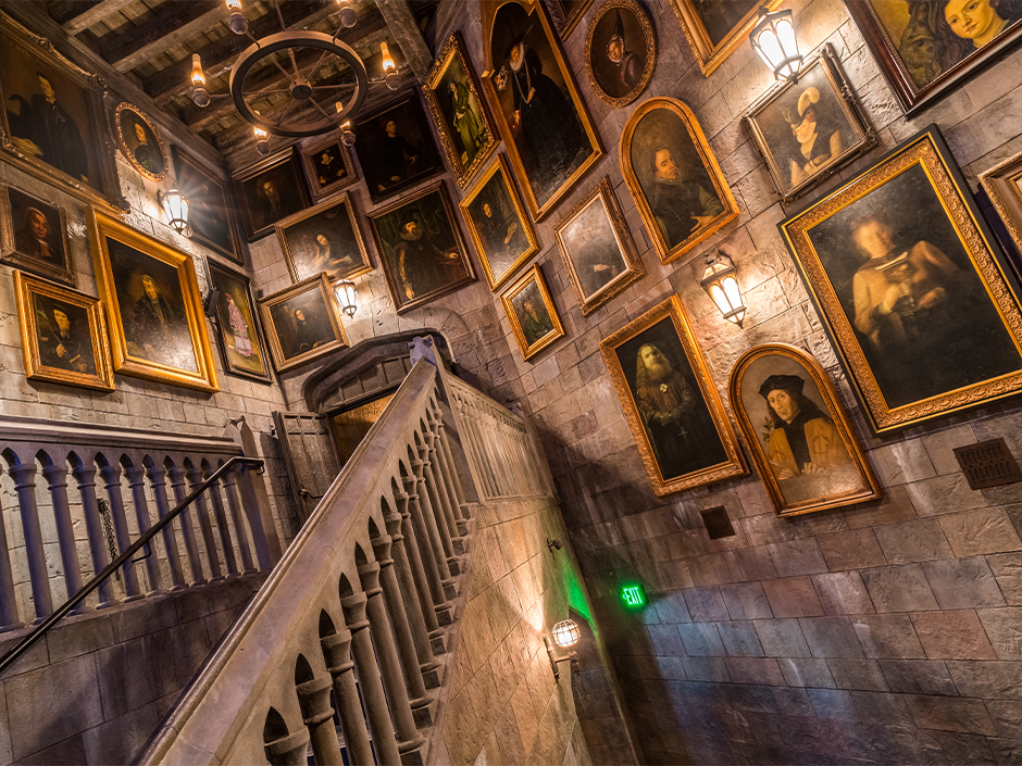 Queue of Harry Potter and the Forbidden Journey in the Wizarding World of Harry Potter. Photographs line the walls centered by a stairwell.