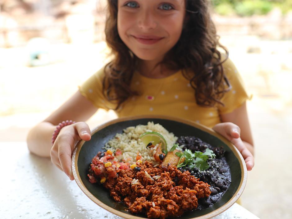 A girl holds a bowl of food