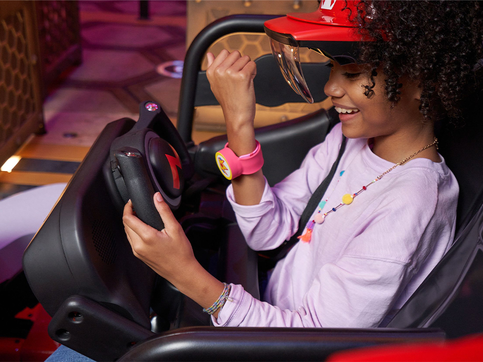 A girl taps her Power-Up Band to the wheel on Mario Kart: Bowser's Challenge at Universal Studios Hollywood. 