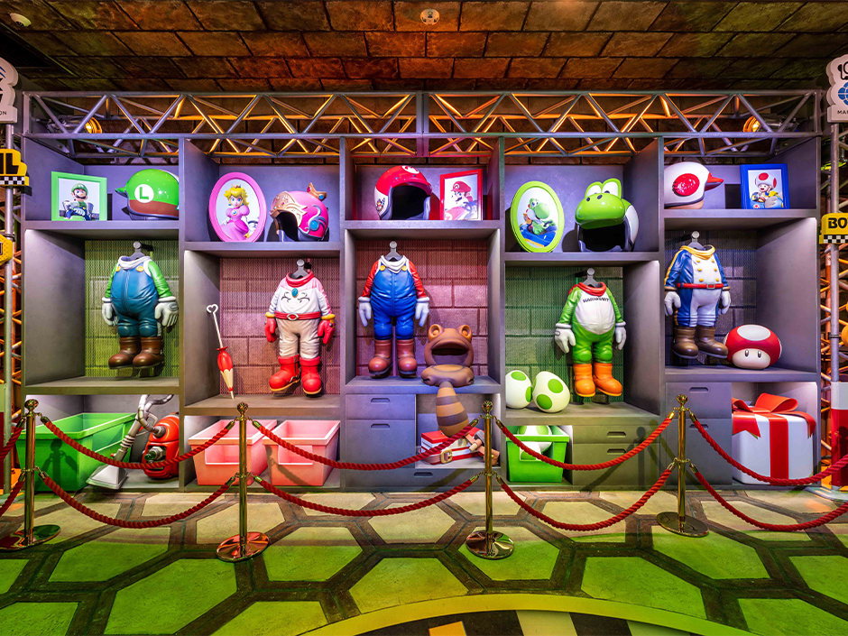 The queue of Mario Kart: Bowser's Challenge. Different racing costumes line the wall.
