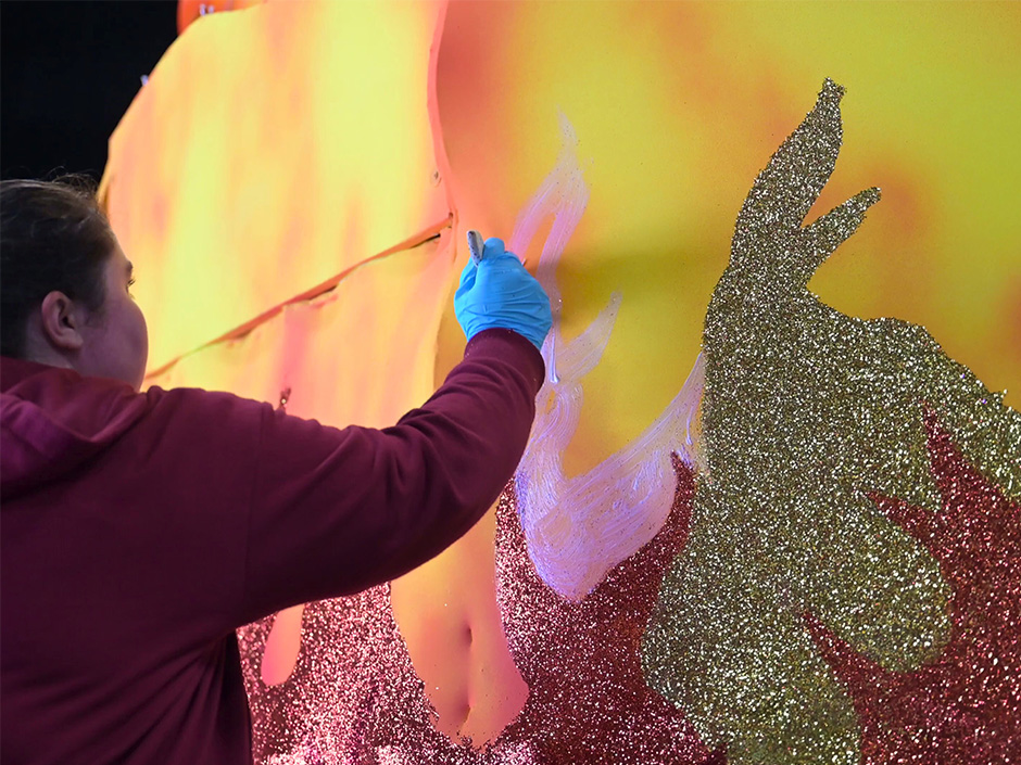 A team member paints a Mardi Gras float