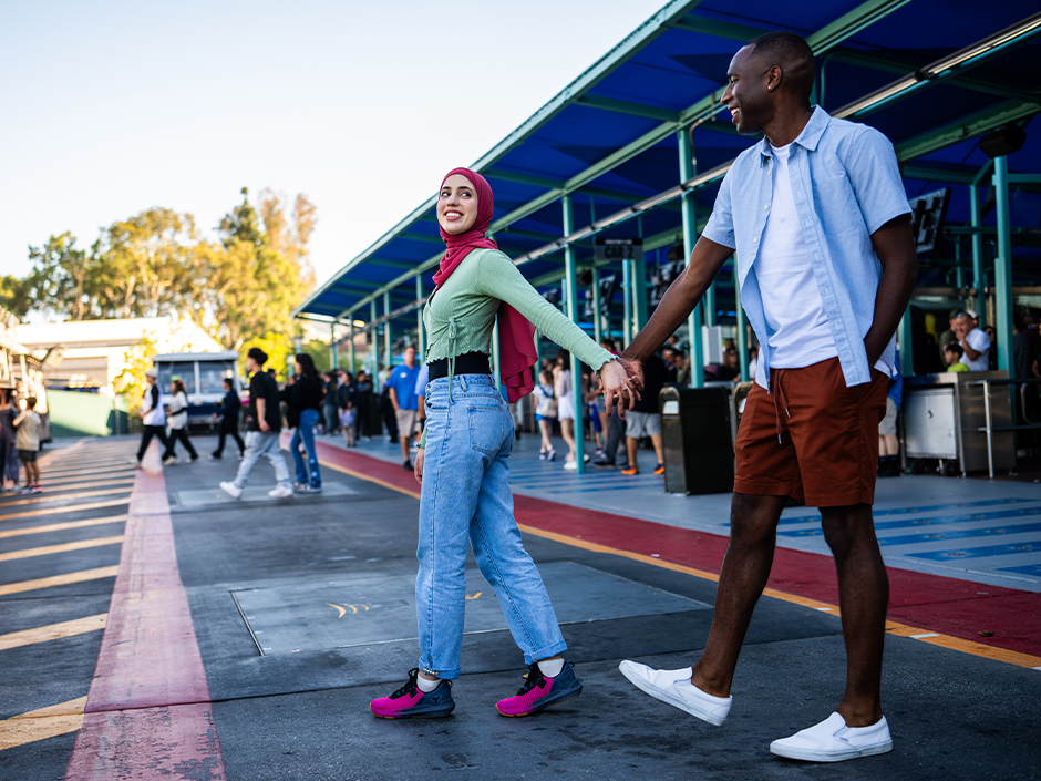 A woman wearing a head scarf holding hands and walking with an African American man.