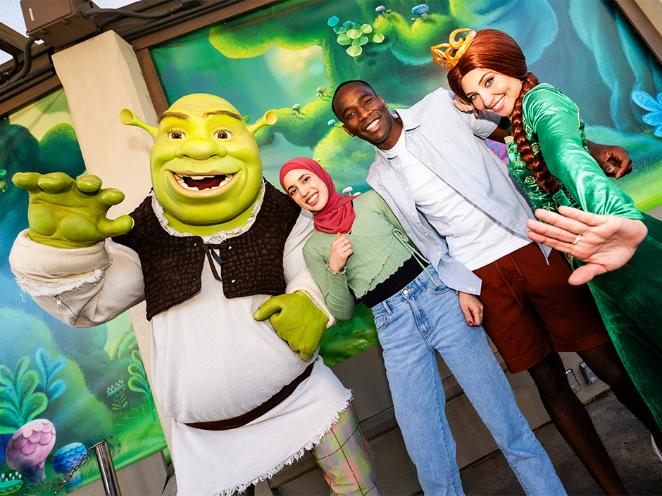 A man and woman posing with Shrek and Fiona.