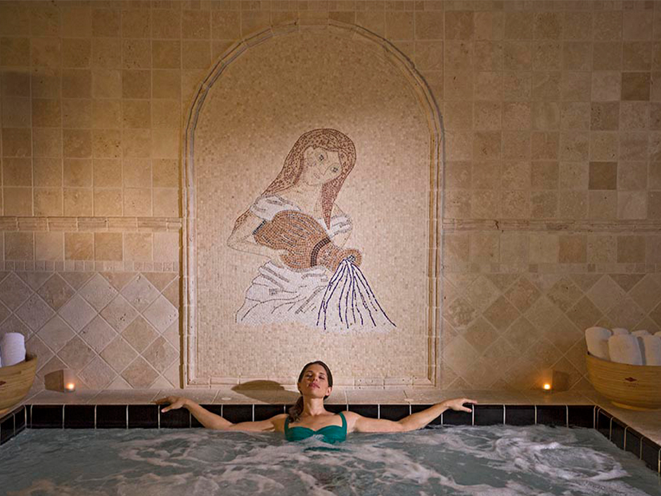 A woman in a green bathing suit relaxing in a spa.