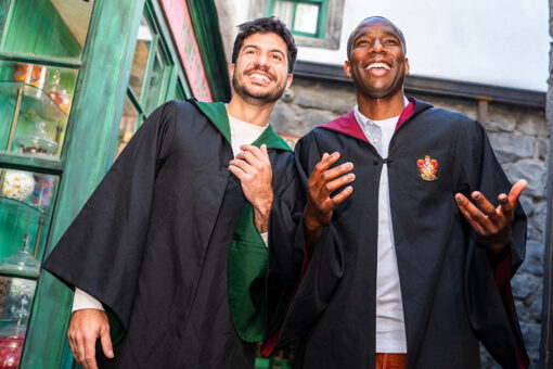 Two men wear Hogwarts house robes in the Wizarding World of Harry Potter.
