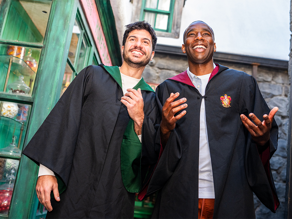 Two men wear Hogwarts house robes in the Wizarding World of Harry Potter.