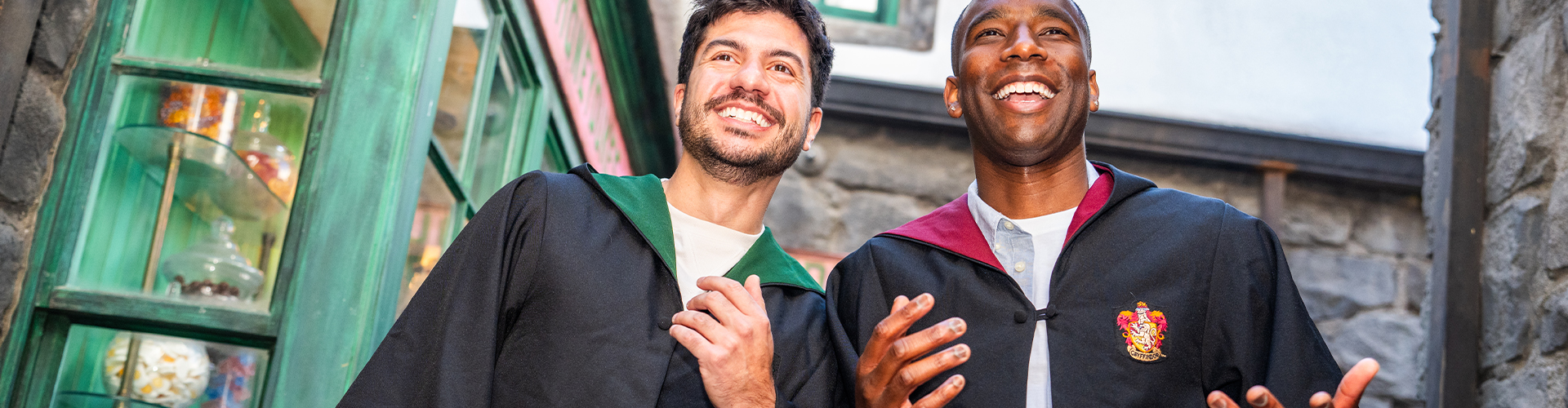 Two men wear Hogwarts house robes in The Wizarding World of Harry Potter.