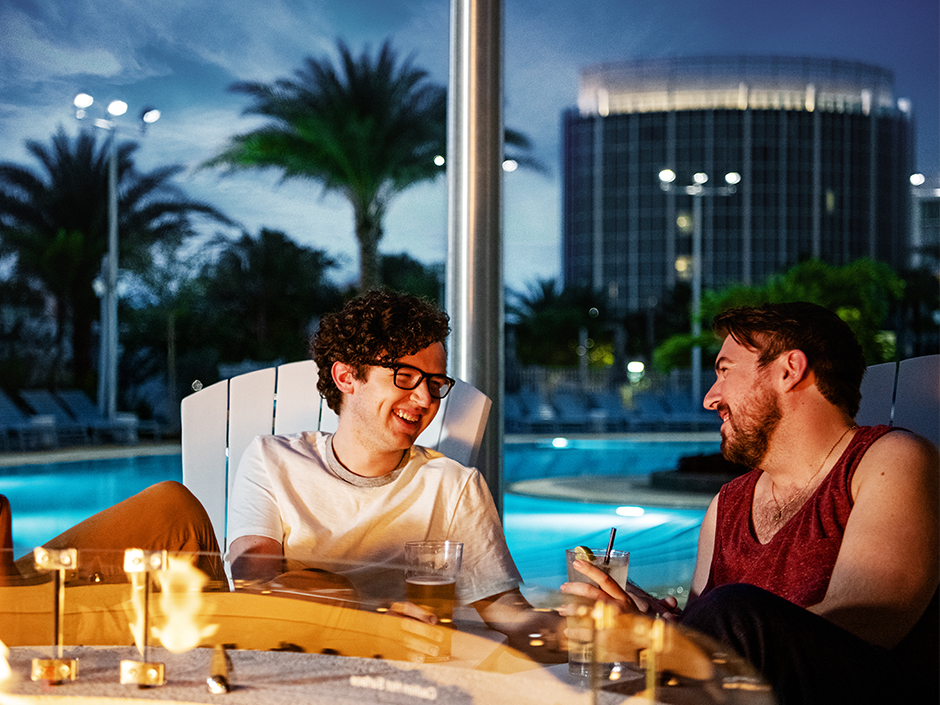 Two men smiling by a fire.