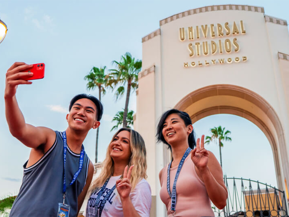3 people posing for a selfie in front of the Universal Studios Hollywood arch.