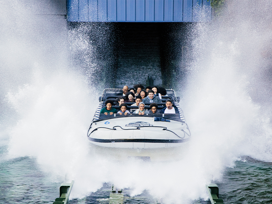 A boat full of guests splashes into the finale of Jurassic World – The Ride at Universal Studios Hollywood.